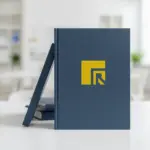 明亮的辦公桌上擺放著印有黃色品牌 Logo 的深藍色書籍,說明在進行商標侵權認定時,商品與服務類別的類似性對商標法侵權的認定